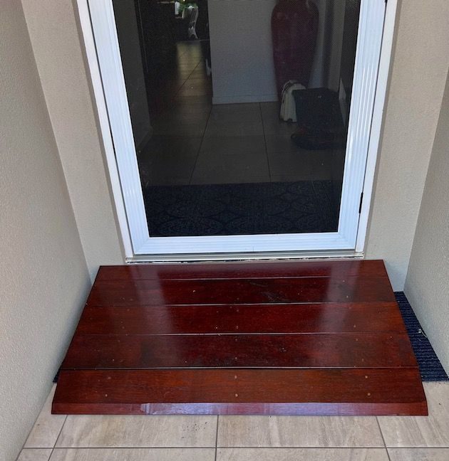 Small timber step stool in front of a glass door