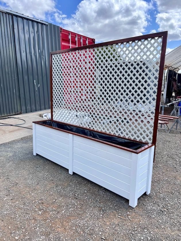White planter box with a brown lattice trellis outdoors