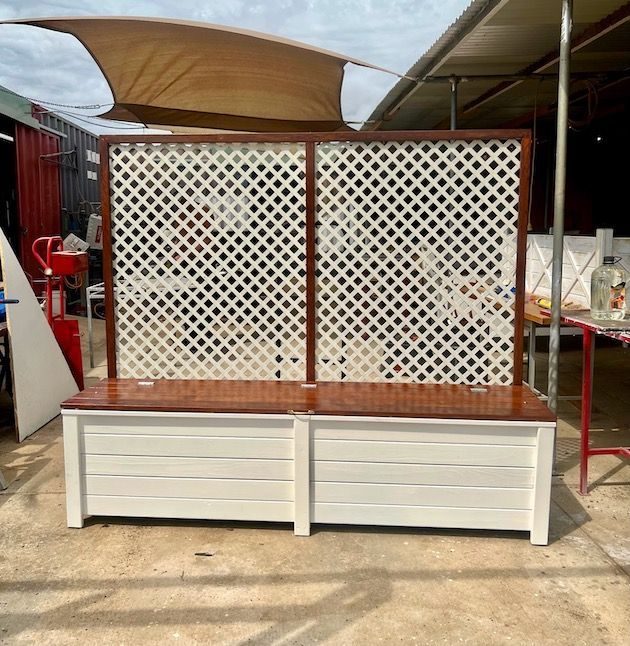 White lattice bench with a timber top in an outdoor market area