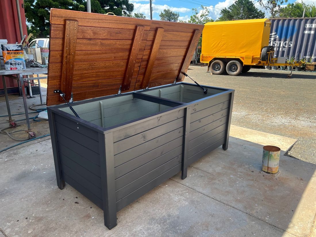 Grey metal raised garden bed with an open timber lid on a patio