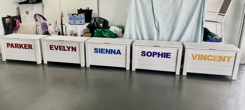 White timber toy boxes personalised with names in a row