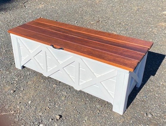 White timber storage bench with a wood top on gravel