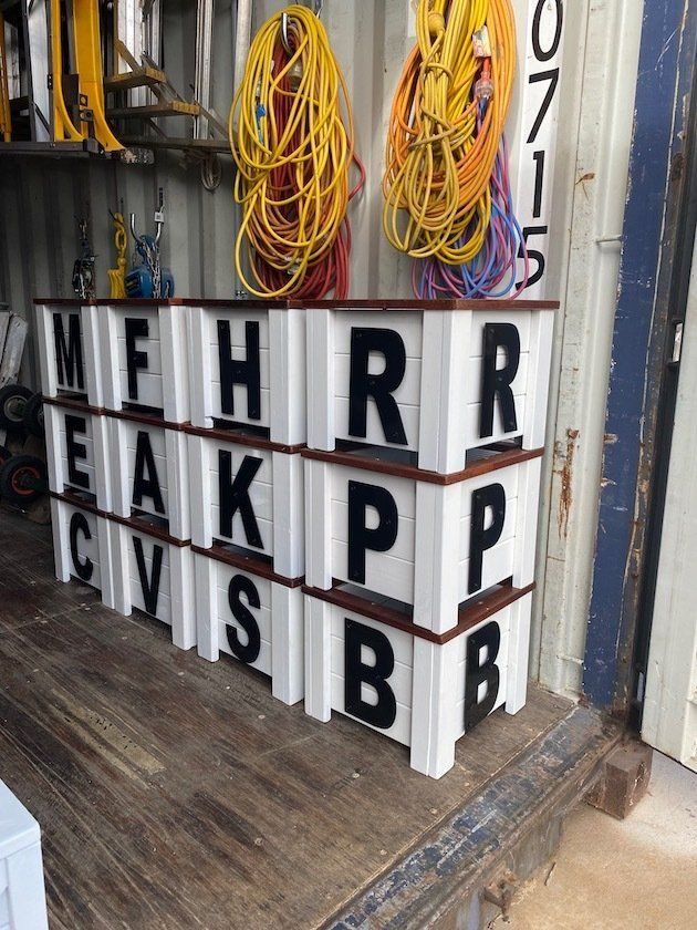 Stacked white lettered display blocks in a workshop
