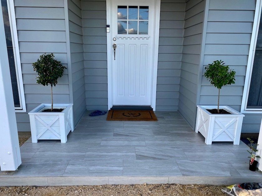 Front porch with a white door and two topiary trees in white Hampton planters