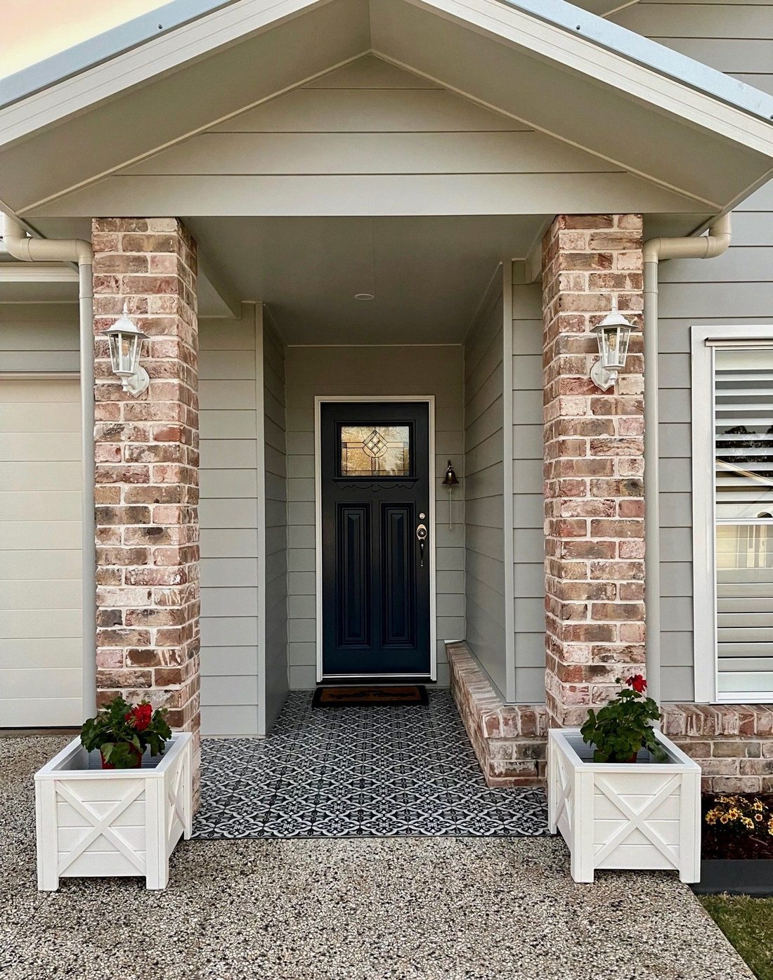 Front porch with brick columns, a blue door and white planters by a walkway