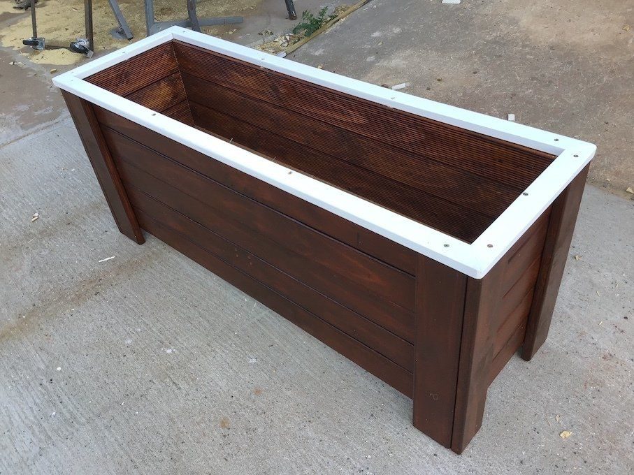 Special-order timber planter box with a white top trim on concrete
