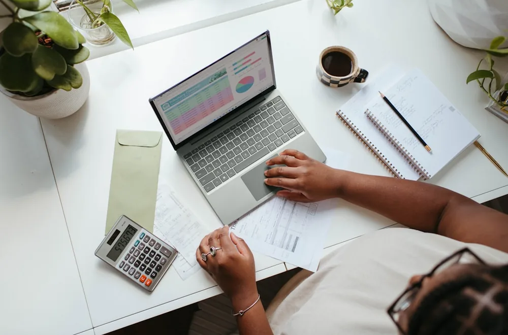Reviewing the numbers — laptop with financial charts, a calculator and statements