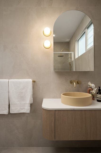 Modern bathroom with wall-mounted brass sconces by Briselec
