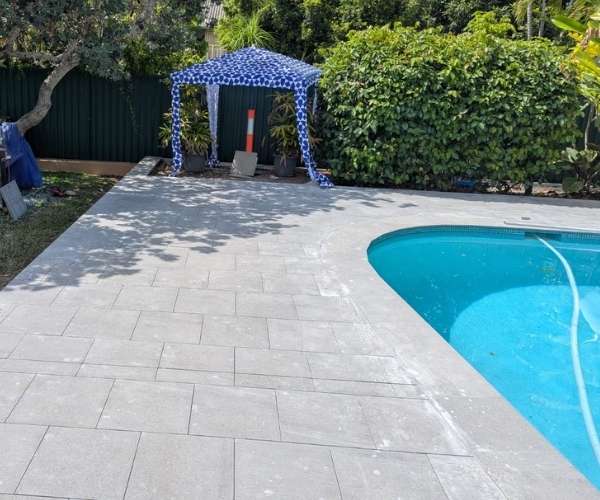 Light stone pool surround tiling by Brisy Tiling