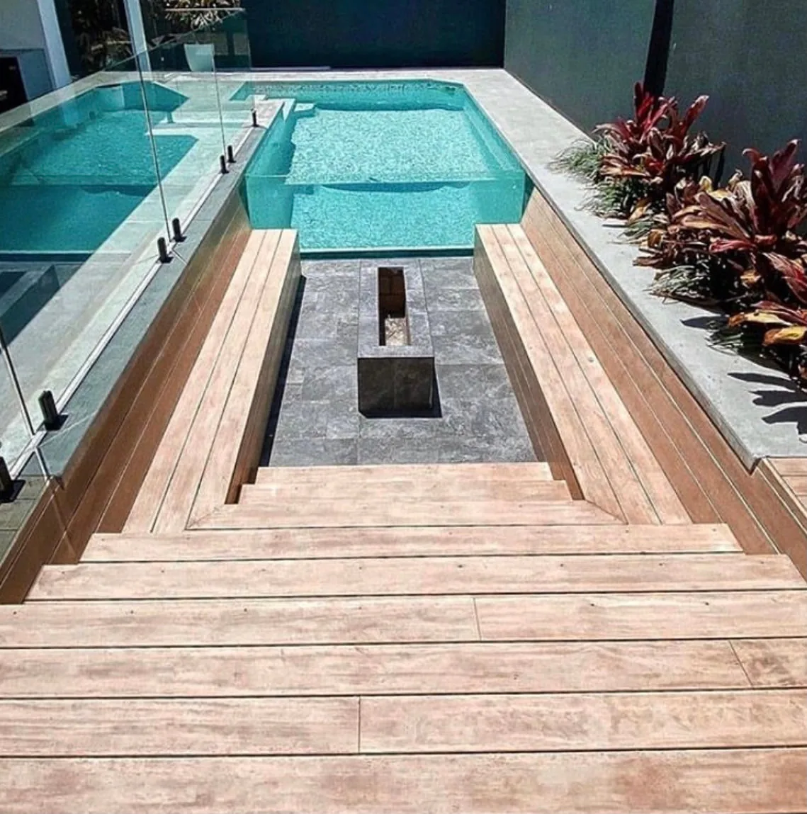 Modern poolside deck with timber surround and built-in steps by C3L Carpentry & Joinery