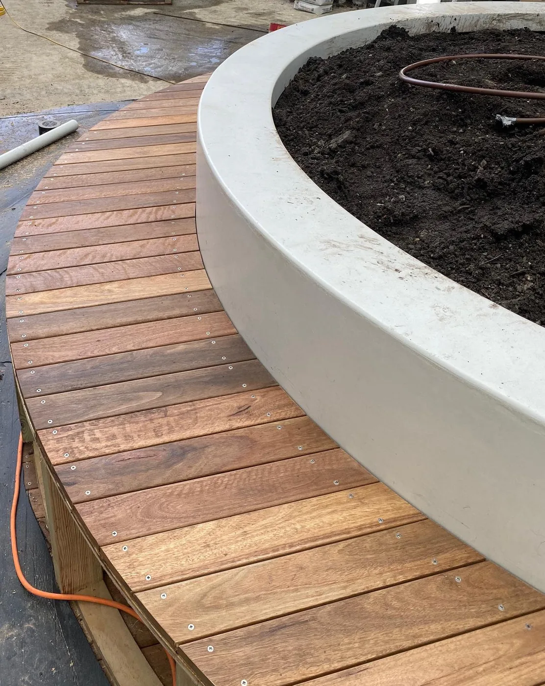 Circular hardwood deck wrapping a concrete planter, built by C3L Carpentry & Joinery