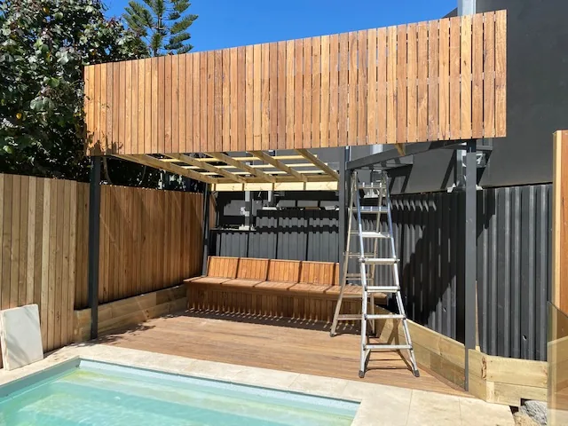 Poolside timber deck with built-in bench and privacy screen by C3L Carpentry & Joinery