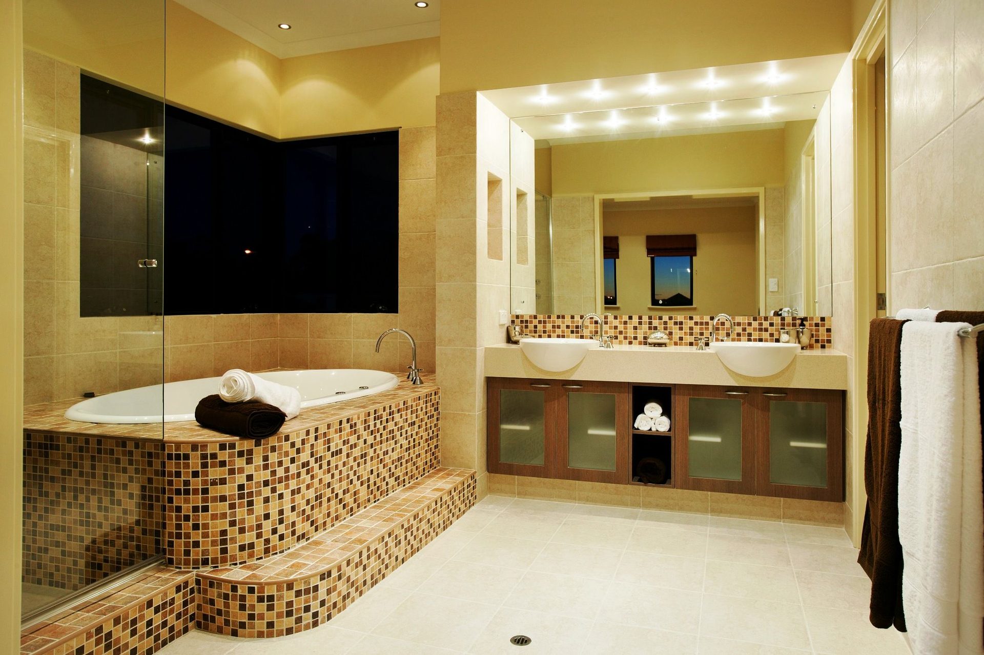 Luxury tiled bathroom with natural stone mosaic, freestanding spa bath and twin vanities by Eminence Tiling