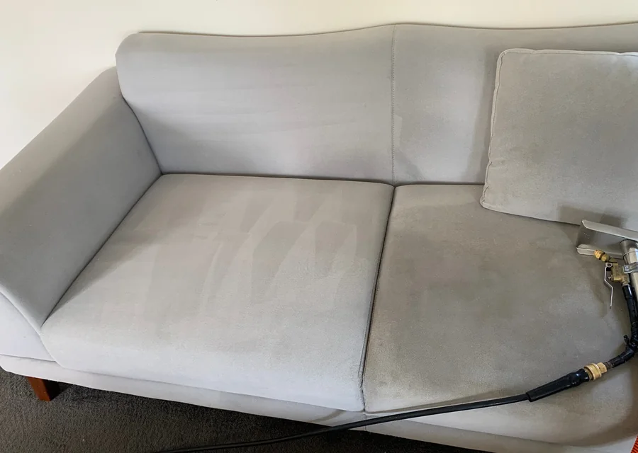 Sofa being cleaned with upholstery tool