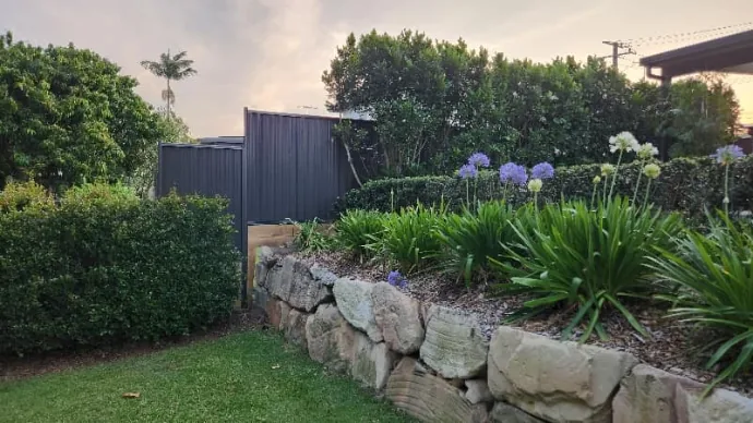 Sandstone retaining wall with established garden