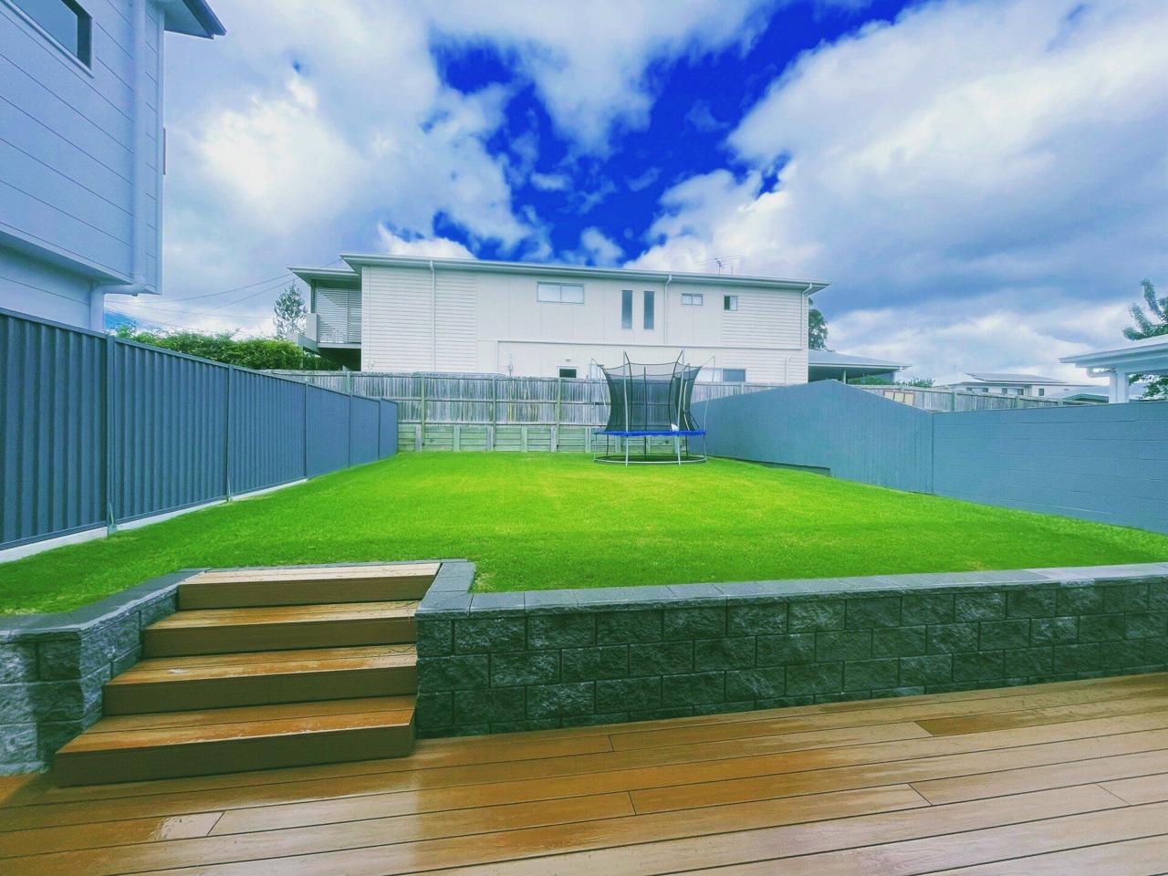 A freshly mown, striped backyard lawn maintained by Greenhow Gardening Service in Brisbane
