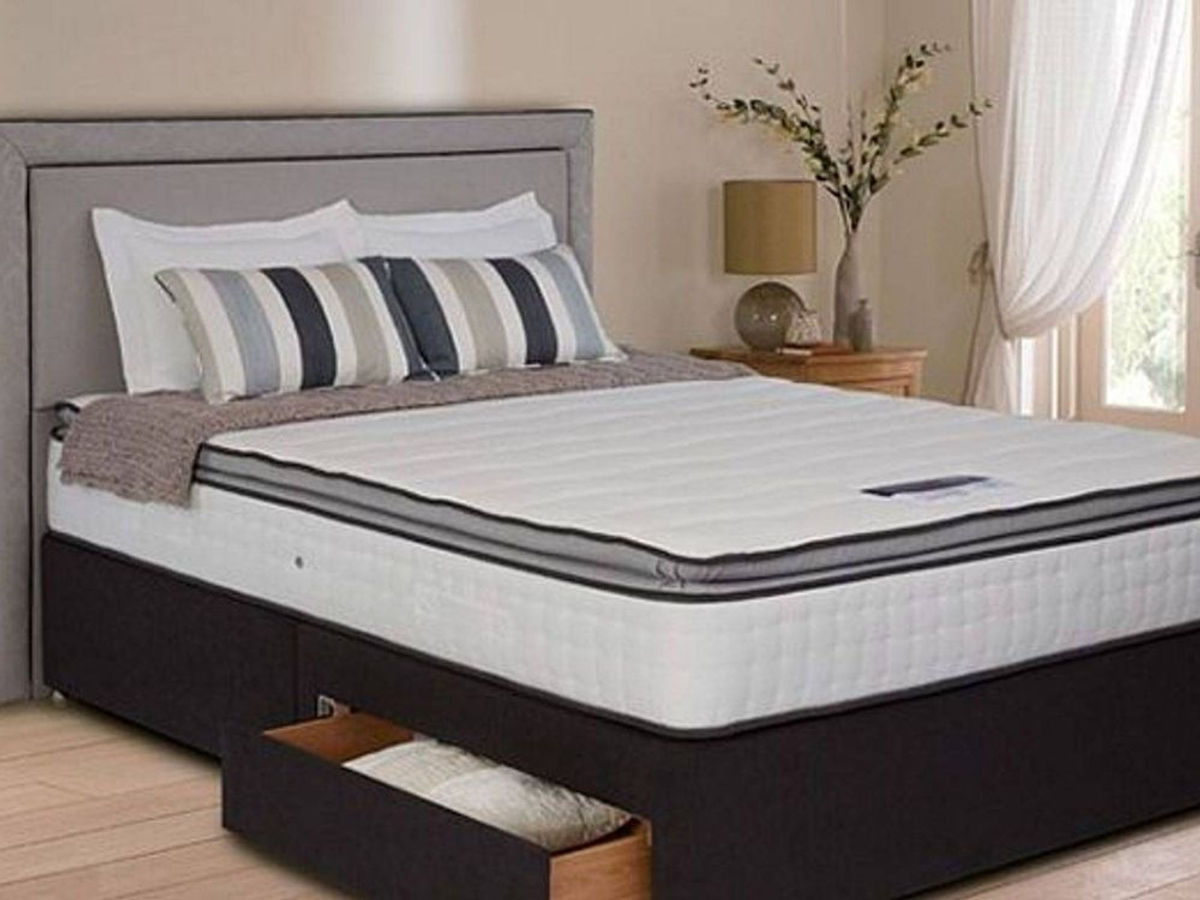A clean mattress on a bed in a bright bedroom