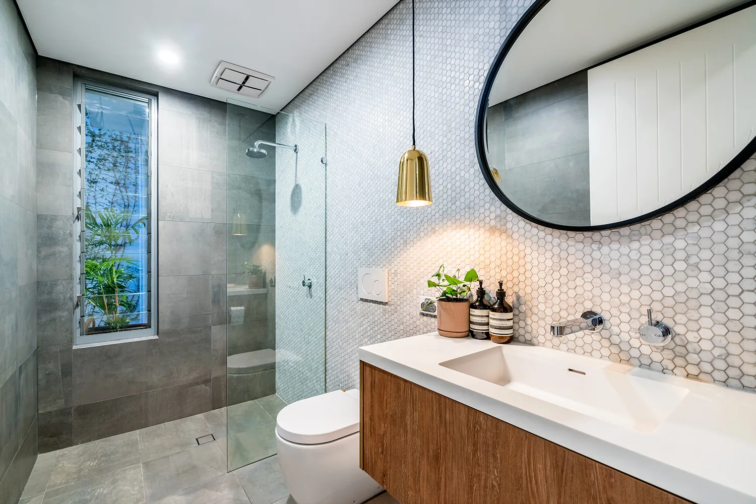 Renovated bathroom with hexagon mosaic tiles and brass pendant