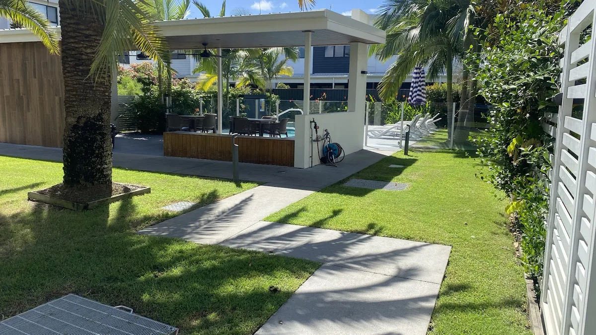 A tidy lawn and garden surrounding a backyard patio area