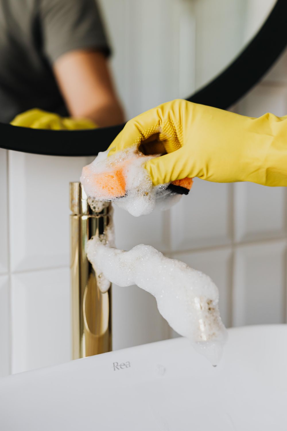 Gloved hand scrubbing a tap during a deep clean