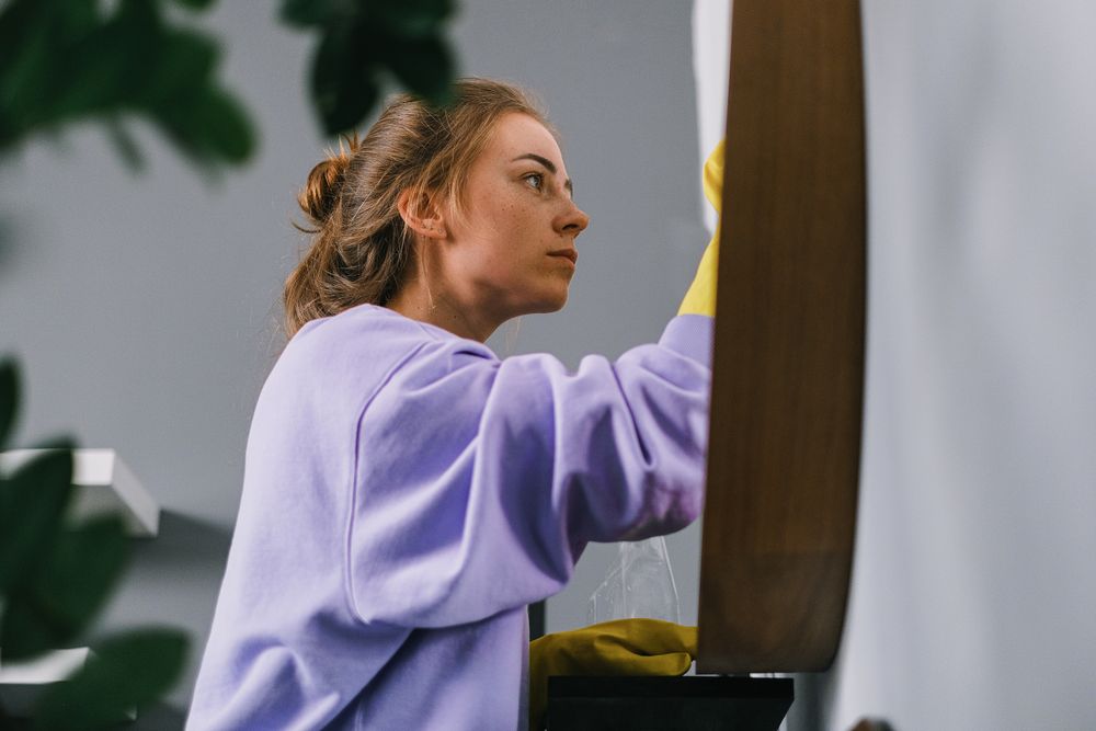 Cleaner wiping a mirror during a regular home clean