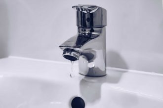 Plumber inspecting a leaking tap