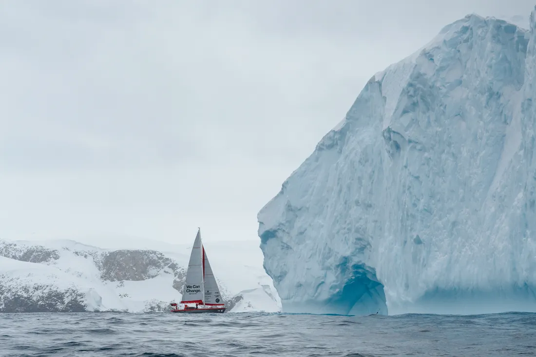 Expedition vessel sailing past an iceberg in polar waters