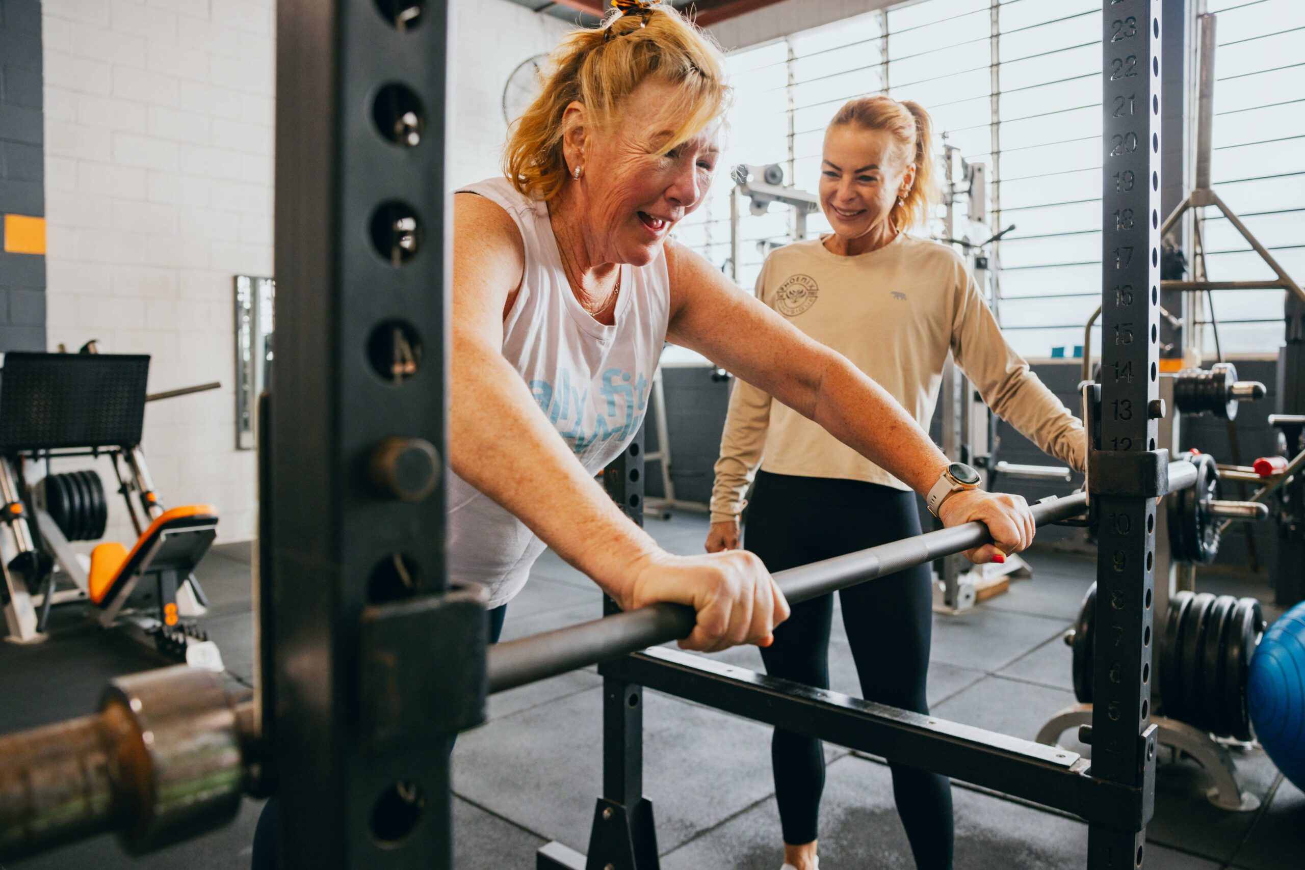 Phoenix Physique member training in the squat rack with a trainer