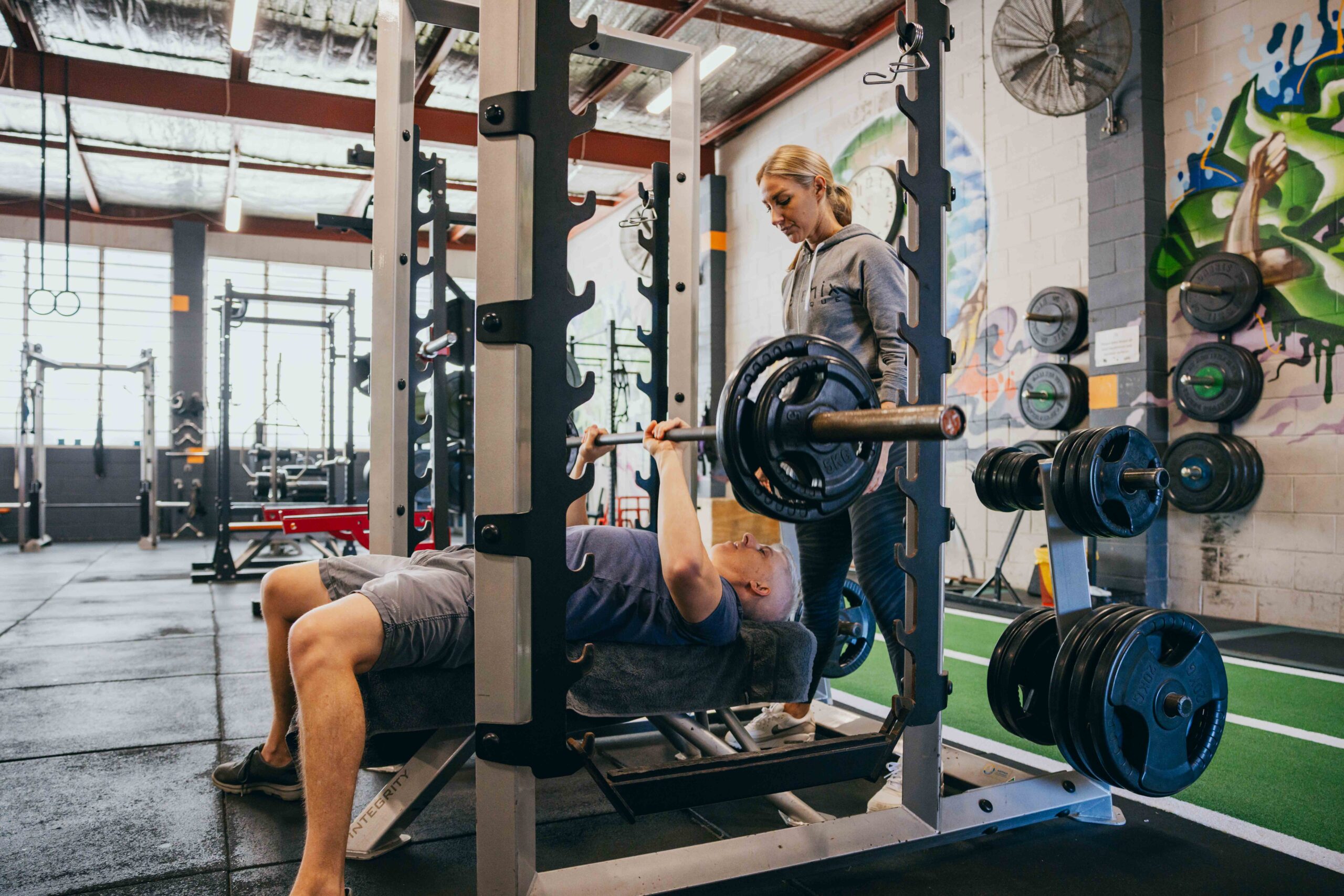 Phoenix Physique trainer spotting a client on the bench press