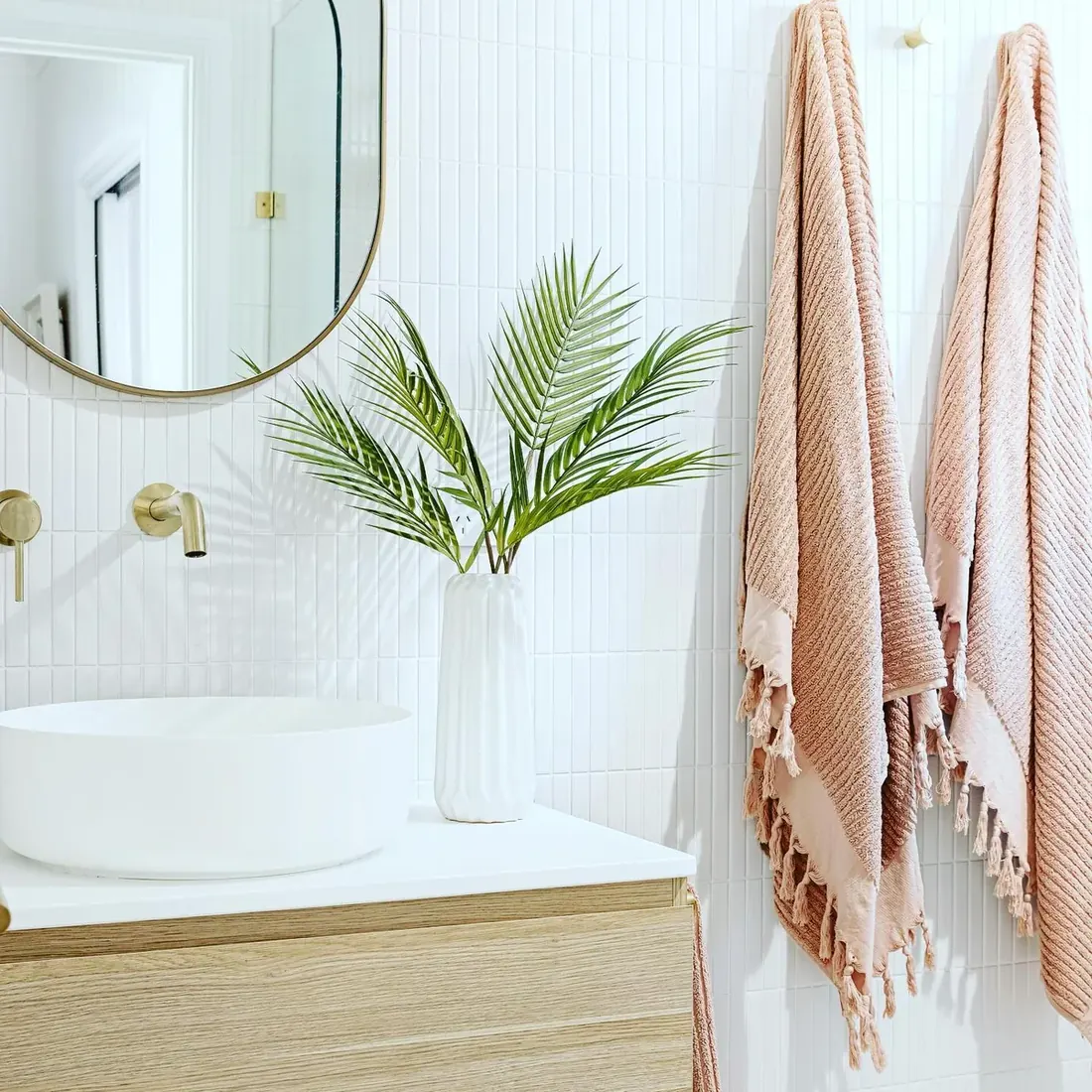 Completed bathroom with white vertical subway tile, brass tapware and a timber vanity
