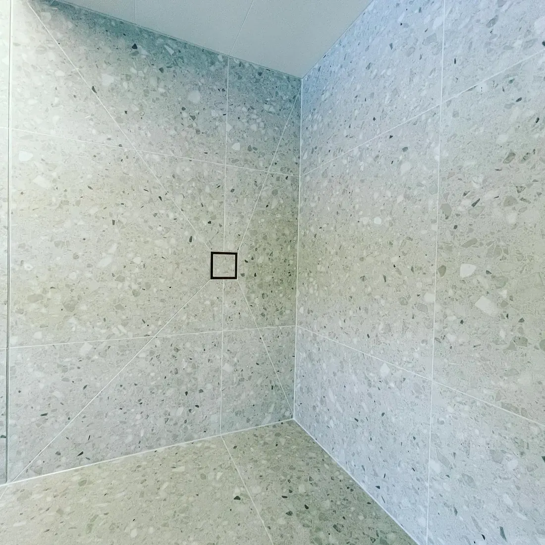 Terrazzo-tiled shower recess in soft grey-green tones
