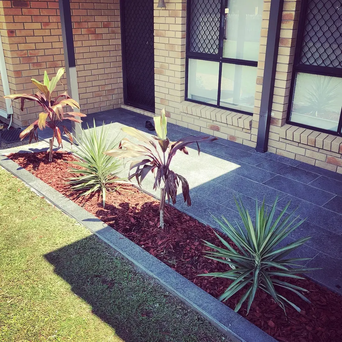 Charcoal outdoor paving with landscaped garden beds