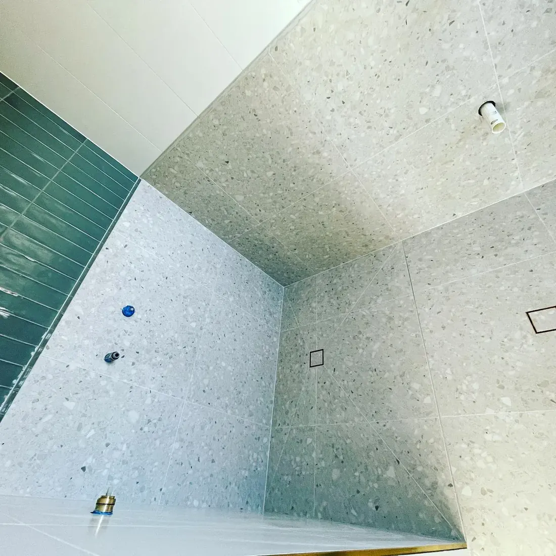 Terrazzo-tiled shower with a green feature tile band