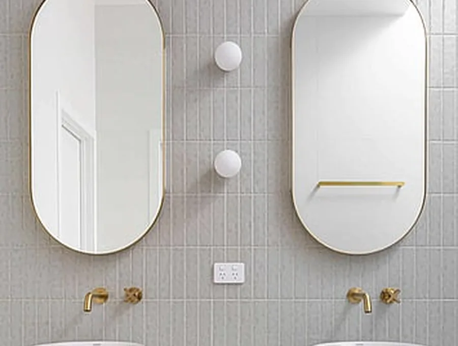 Twin oval mirrors above a brass-fitted vanity in a Brisbane bathroom