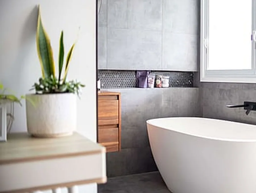Freestanding bath with black tapware and concrete-look tiles