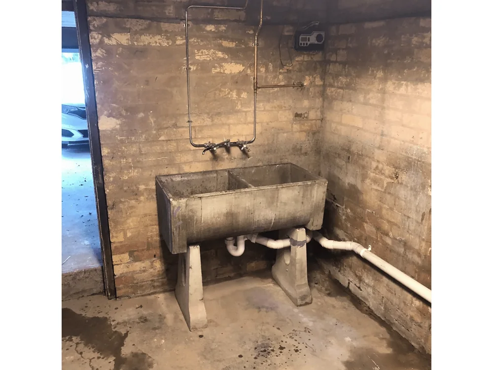 Plumbing maintenance work on a concrete laundry trough