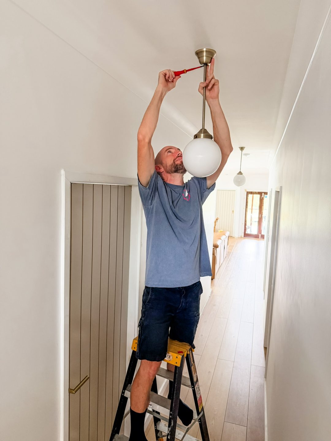 Chris from SafePower Solutions installing a light fitting in a Brisbane home