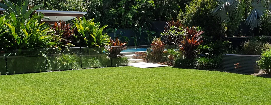 Healthy green lawn and tropical garden beside a pool