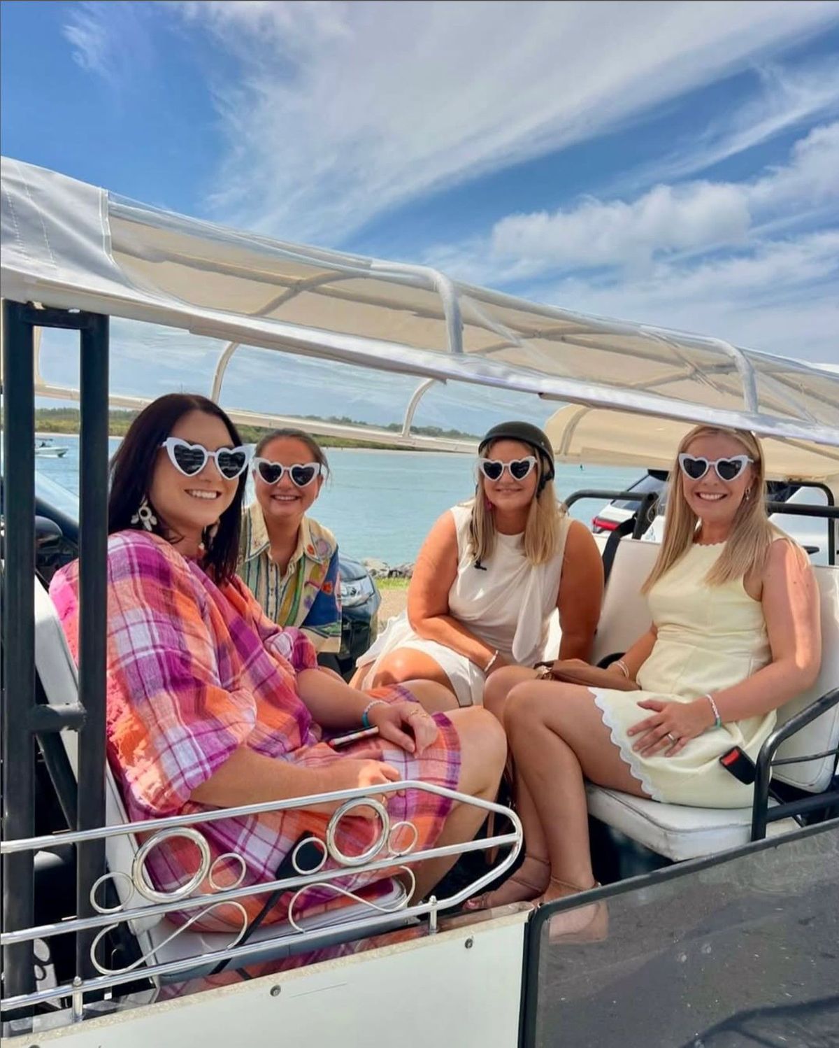 Friends smiling on a tuk tuk by the water