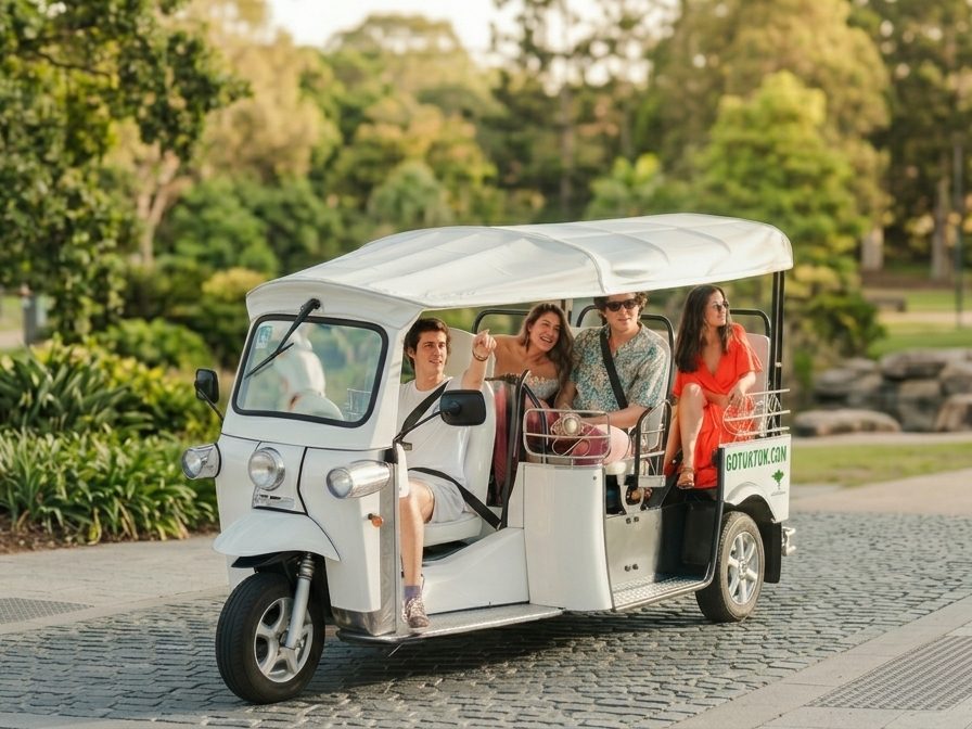 Four guests riding an electric tuk tuk through a Brisbane park at golden hour